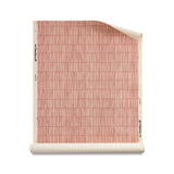 Roll of grasscloth with dashed striped grid in cream on clay pink.