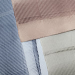 Pile of wallpaper swatches with dimensional combed patterns in navy, mauve and tan colorways.