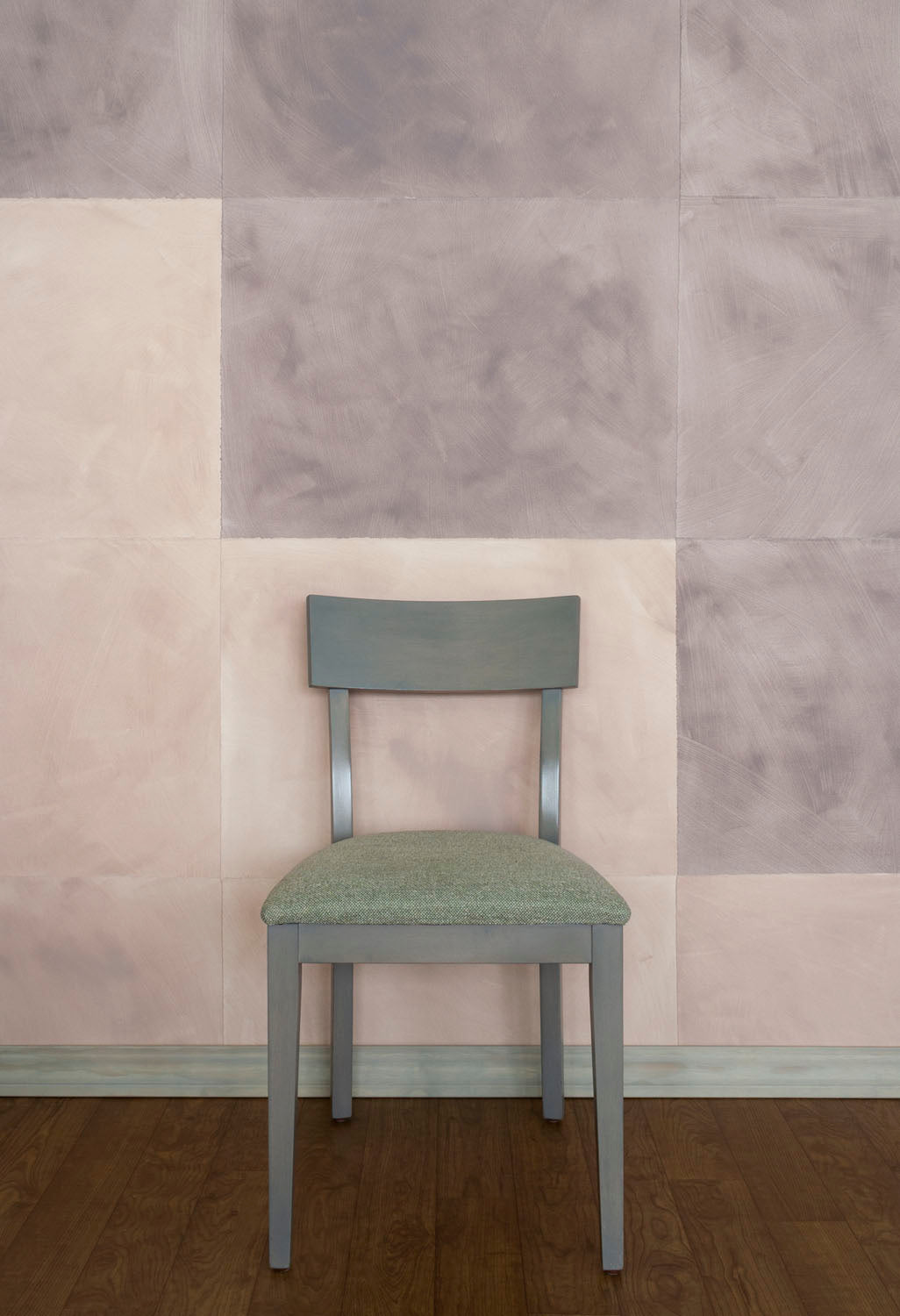A chair stands in front of a wall papered in a domino pattern in sheets of dusty rose and mauve.