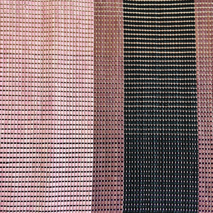 Close-up of a woven leather rug in an irregular stripe print in shades of pink, purple and black.