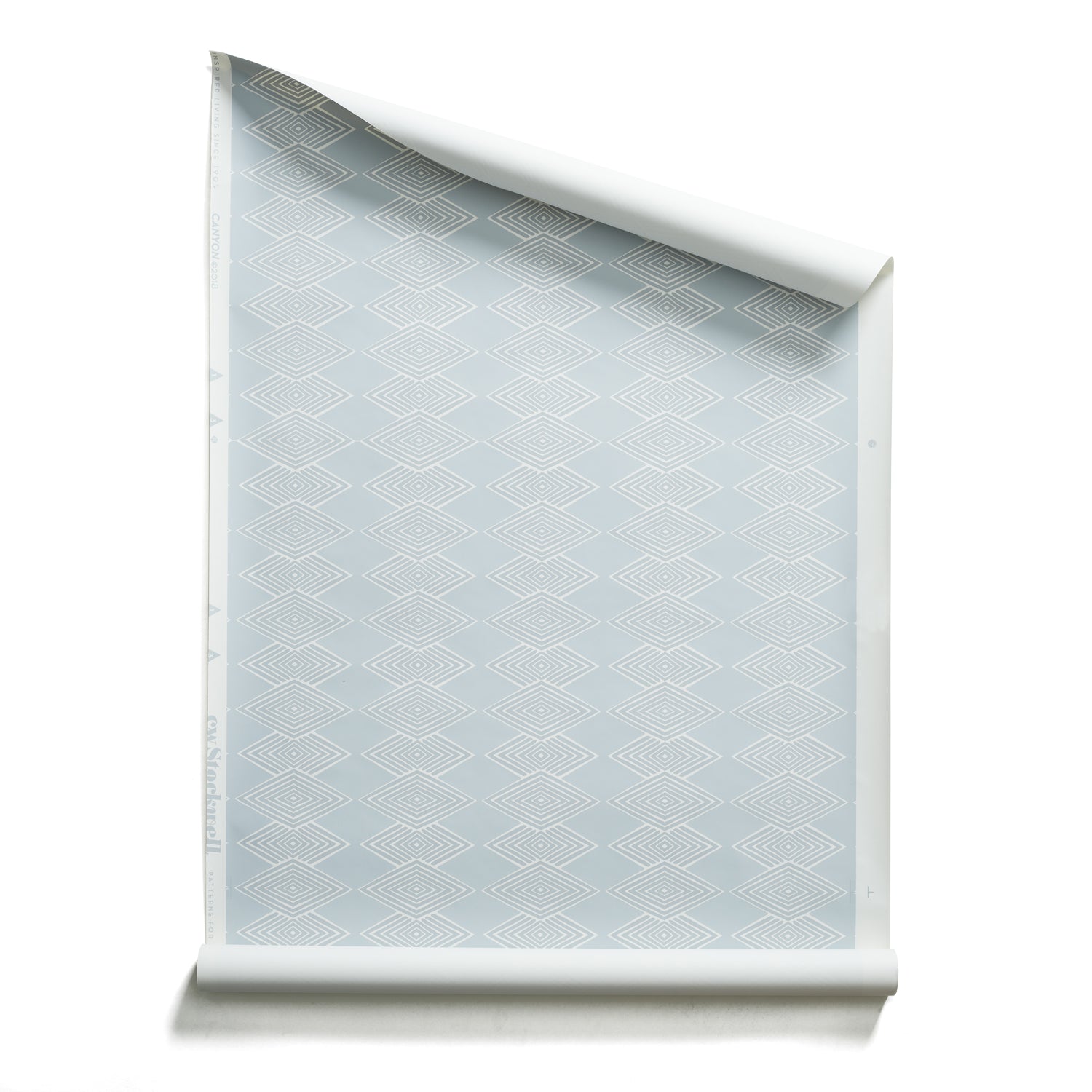 Roll of wallpaper with linear stacked diamond stripe in shades of pale blue.