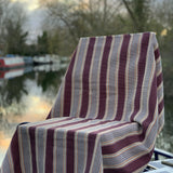 Striped fabric draped over a chair with a blurred background of water and trees