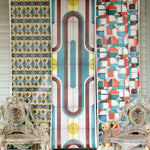 Porch setting with three panels of wallpaper with geometric stained glass patterns and ornate chairs.