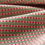 Lightly folded patterned fabric with pink dots and green stripes on a white background