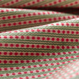Lightly folded patterned fabric with pink dots and green stripes on a white background