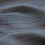 Lighly folded fabric with navy dots and blue stripes on a white background