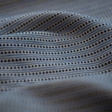 Lighly folded fabric with navy dots and blue stripes on a white background