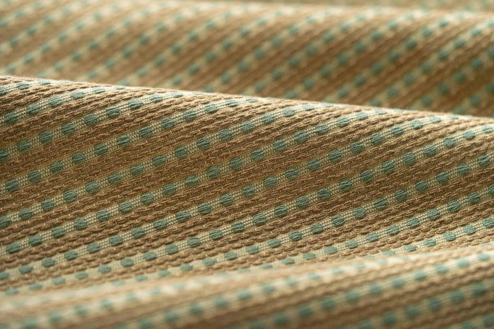 Lightly folded fabric with green dots and tan stripes on a white background
