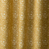 Draped linen fabric in a repeating chrysanthemum pattern in white on a mustard field.