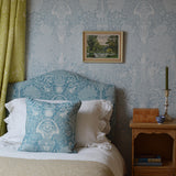 Bedroom with floral headboard and pillows, framed picture on wall, and wooden nightstand.