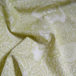 Fabric with intricate white floral and leaf pattern on a light green background