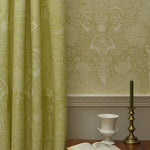 Room with green patterned wallpaper and a table with an open book and decorative items.