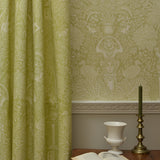 Room with green patterned wallpaper and a table with an open book and decorative items.