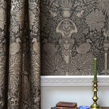 Decorative curtain with intricate patterns and a candlestick holder on a table.