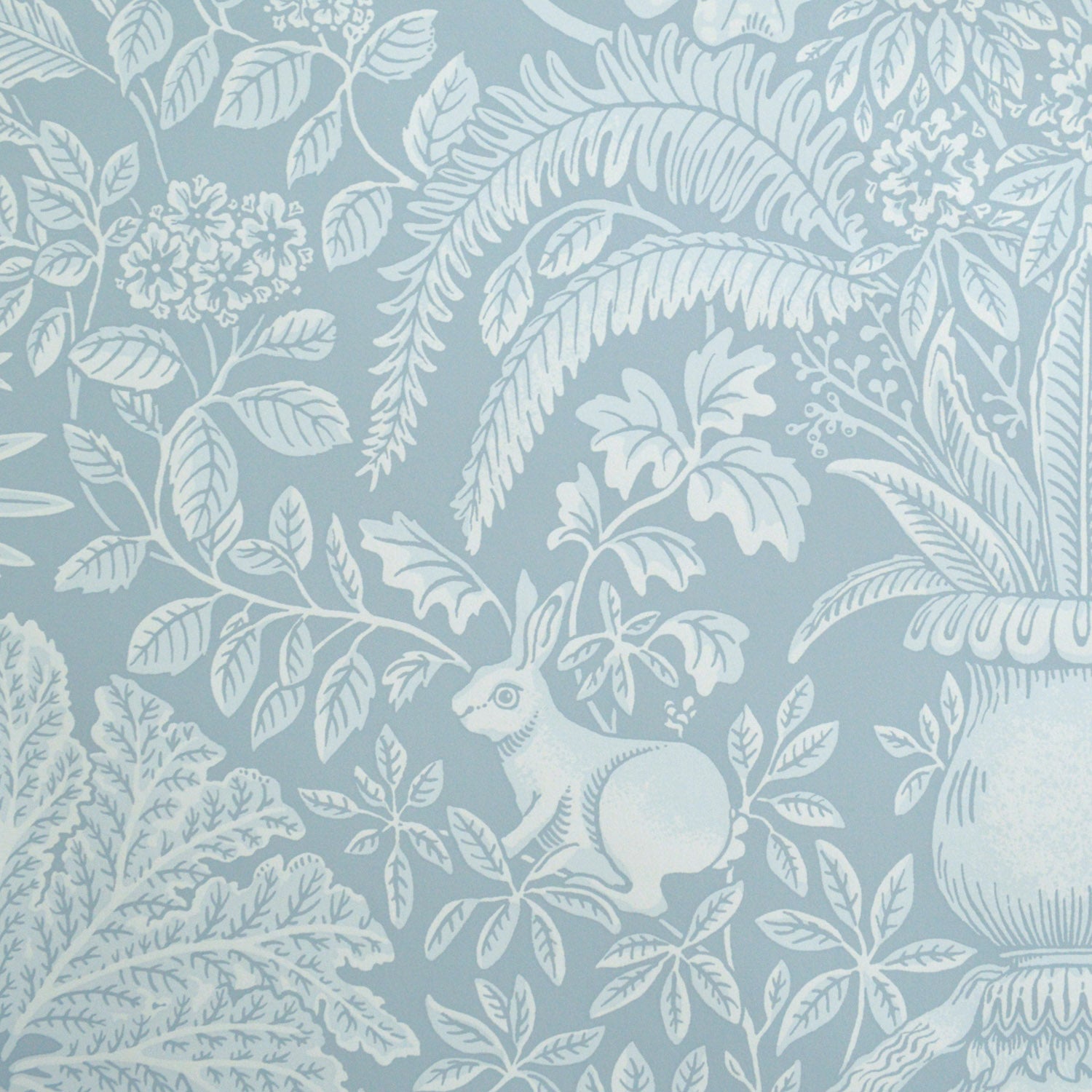 Patterned wallpaper with white leaves and a rabbit on a blue background