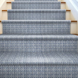 Staircase with patterned blue and white runner on wooden steps.