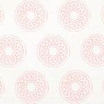 Detail of fabric in a repeating circular geometric print in light pink on a white field.