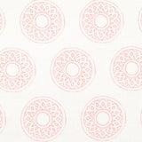 Detail of fabric in a repeating circular geometric print in light pink on a white field.
