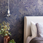 Detail of a bedroom with a statement wall papered in a dense coral print in gold on a navy field.