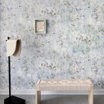 A modernist living tableau with a wall papered in a watercolor painted print in blue, green, yellow and white.
