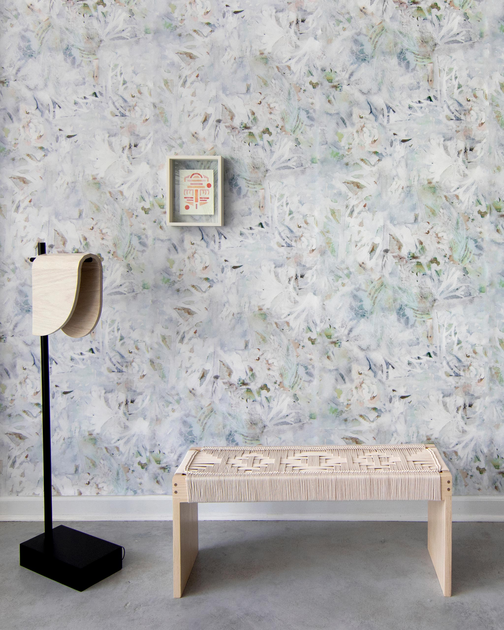 A modernist living tableau with a wall papered in a watercolor painted print in blue, green, yellow and white.