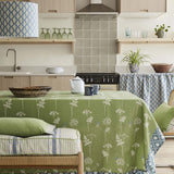 A cozy kitchen and dining space with a table covered in a tablecloth in a green flower and butterfly fabric.