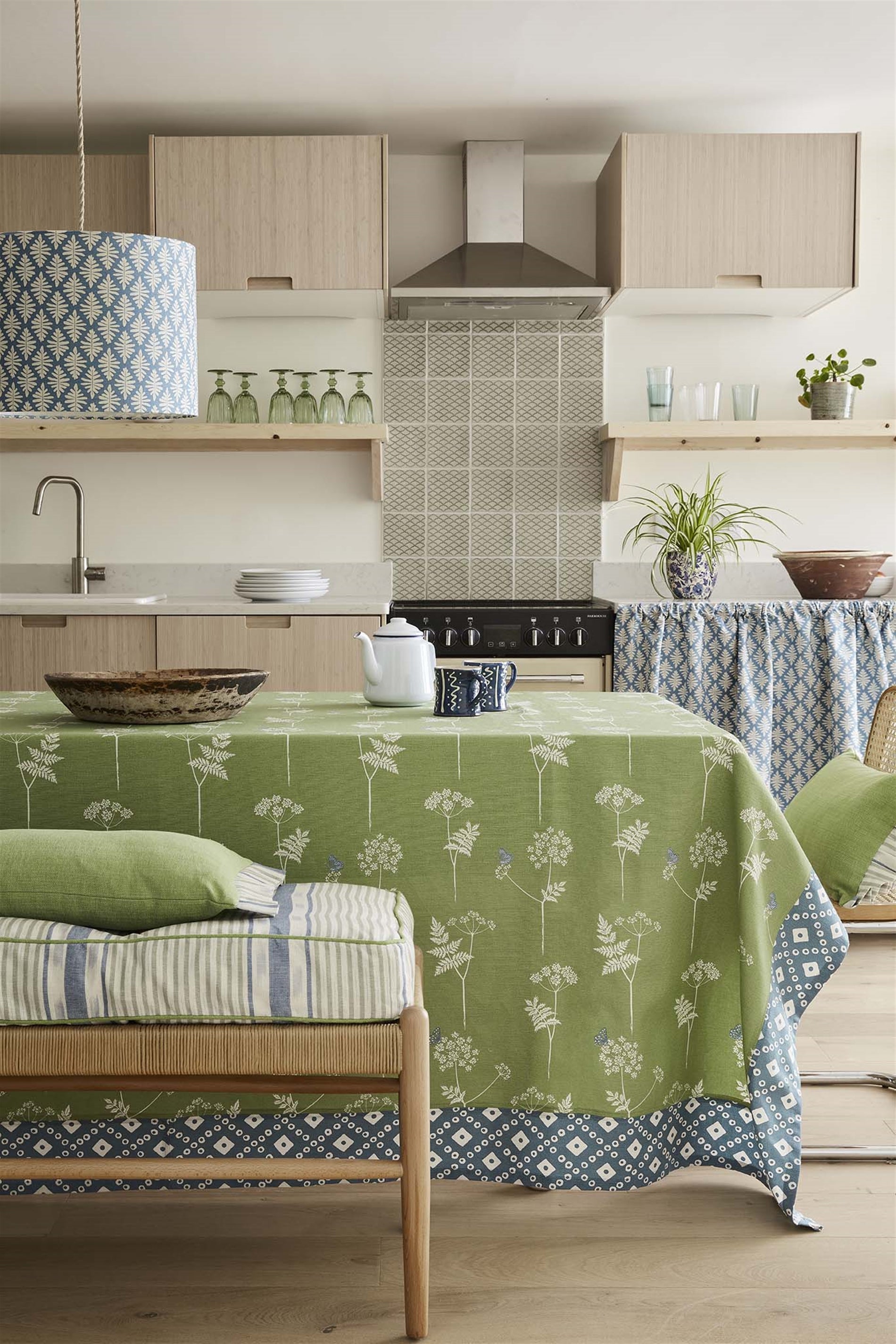 A cozy kitchen and dining space with a table covered in a tablecloth in a green flower and butterfly fabric.