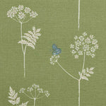 Detail of fabric in a playful flower and butterfly print in white and blue on a green field.