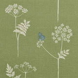 Detail of fabric in a playful flower and butterfly print in white and blue on a green field.