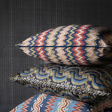 Three patterned pillows on a dark textured surface