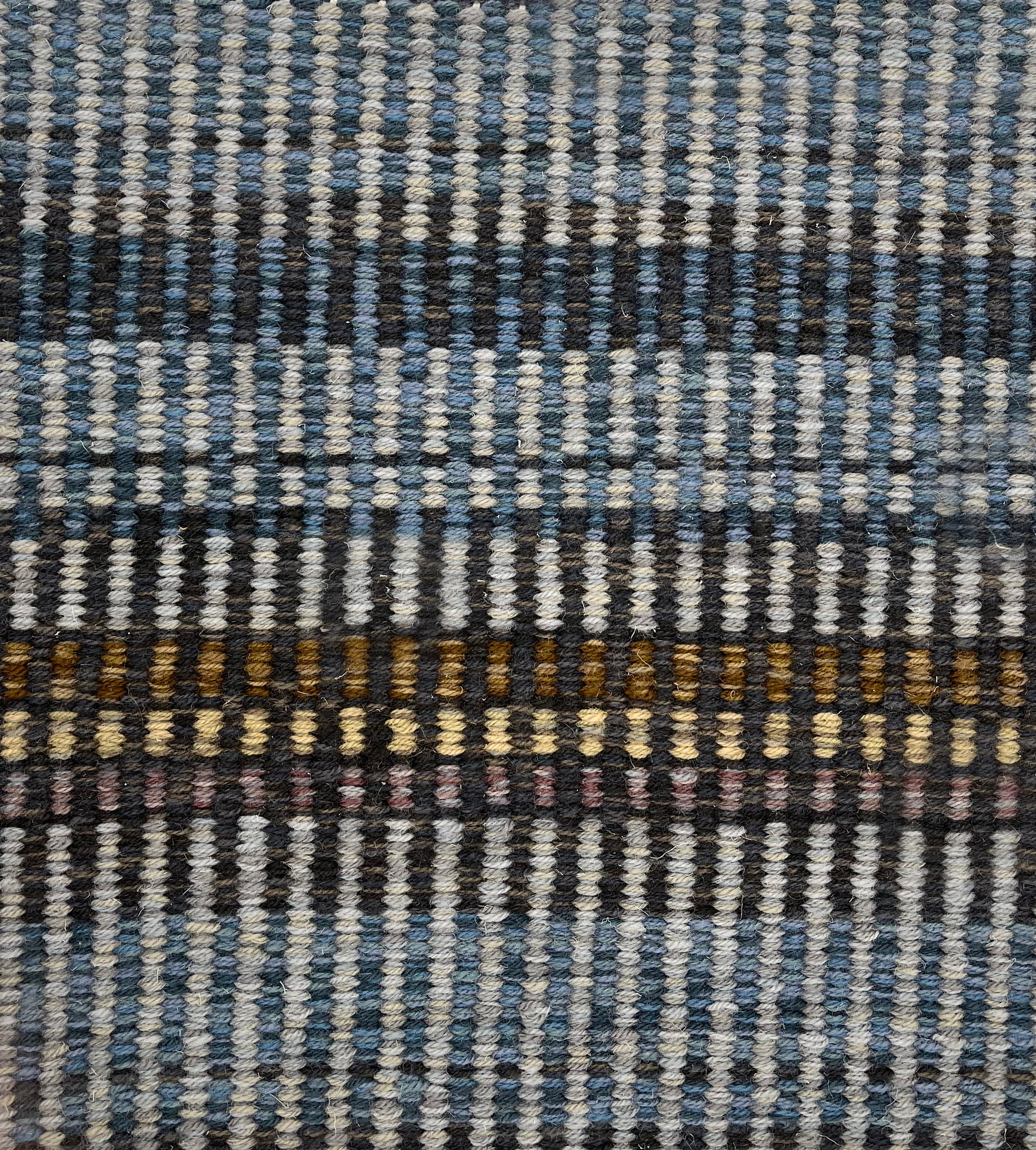 Handwoven carpet in a variegated stripe in shades of blue blue, charcoal, brown,  yellow and tan. 