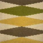 Close-up of a patterned rug with geometric shapes in green, brown, and beige.