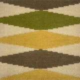 Close-up of a patterned rug with geometric shapes in green, brown, and beige.