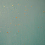 Detail of a wallpaper in a random splattered pattern in metallic gold on a green field.