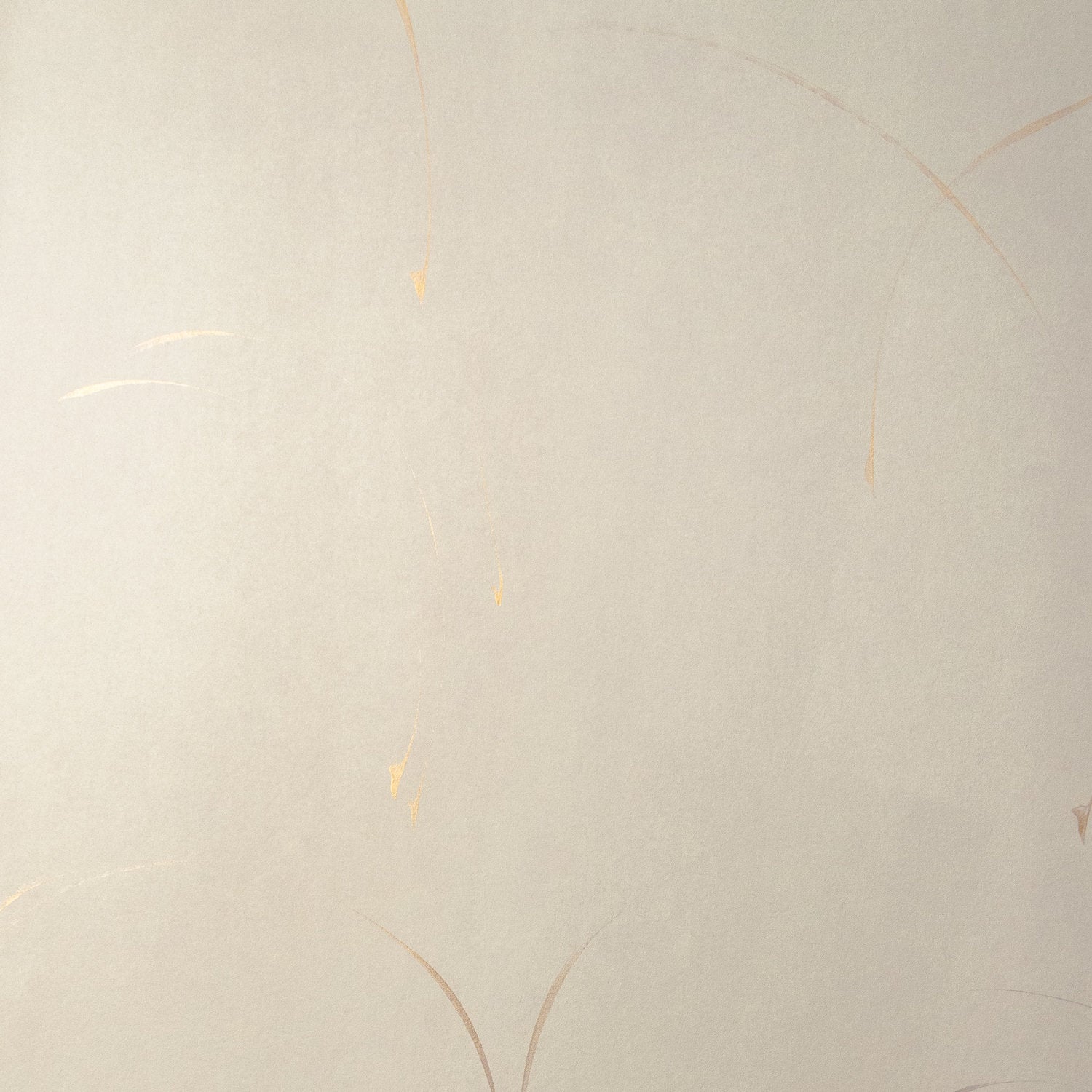 Detail of a wallpaper in an elongated paint splatter pattern in metallic gold on a cream field.