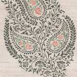 Detail of fabric in a botanical paisley in shades of green pink on a tan field.