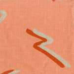 Fabric in a painterly dashed pattern in tan and red on a coral field.