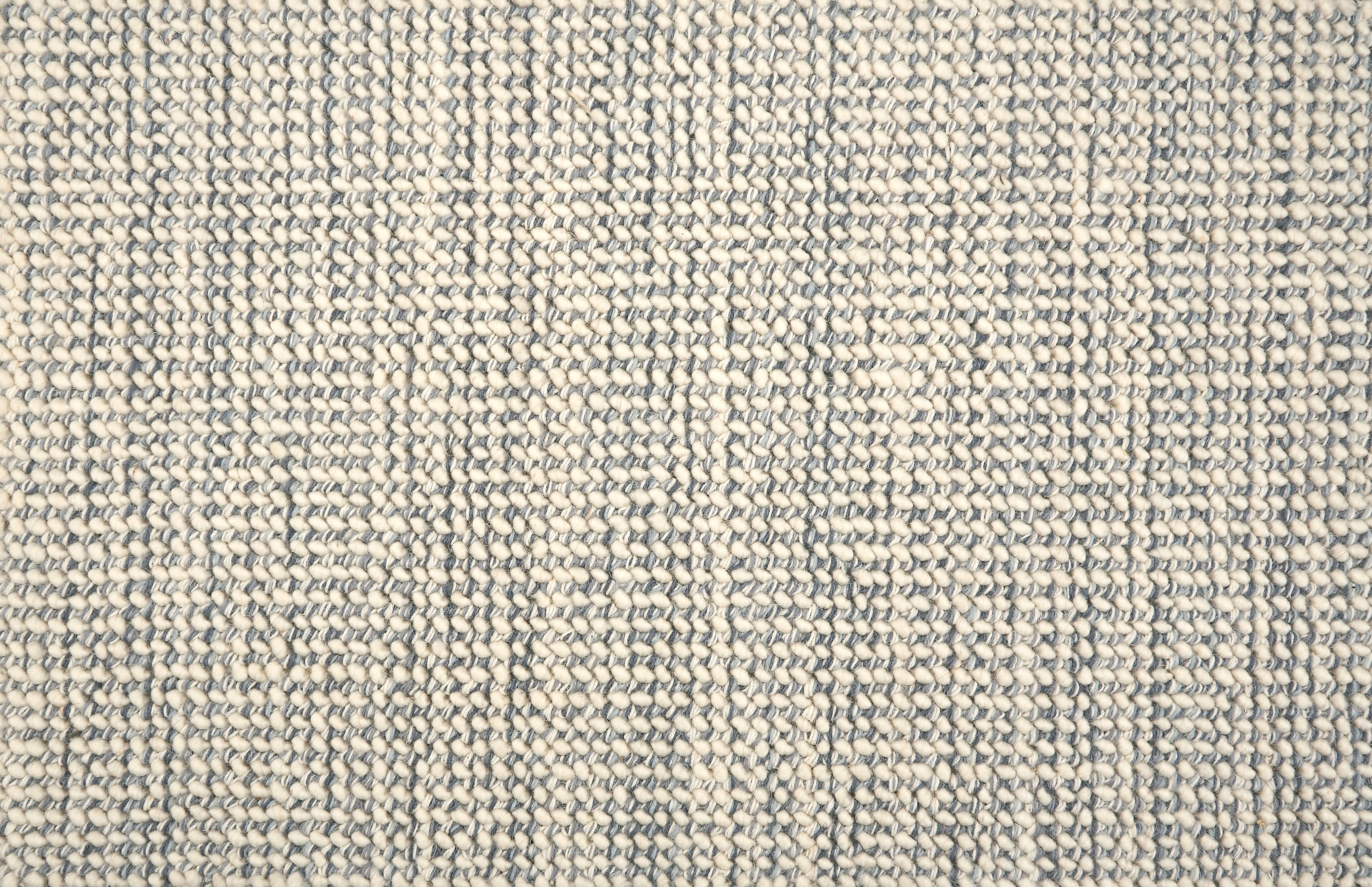 A close-up of a broadloom carpet with a woven texture in cream and slate blue.
