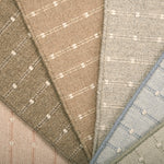A close-up fan arrangement of striped broadloom carpet swatches in soft neutral and pastel tones, including beige, taupe, light gray, blush pink, and pale blue, each with a subtle stripe pattern.