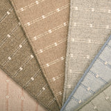 A close-up fan arrangement of striped broadloom carpet swatches in soft neutral and pastel tones, including beige, taupe, light gray, blush pink, and pale blue, each with a subtle stripe pattern.