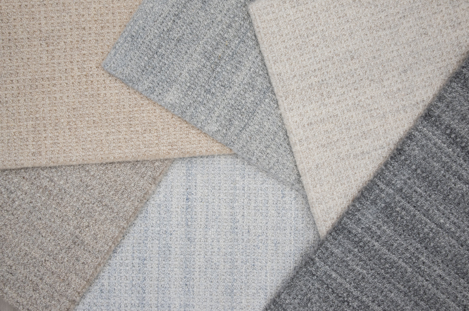 Close-up of various textured gray and beige carpet samples.