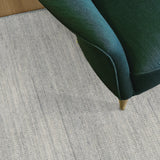 Green chair corner on a textured light gray carpet
