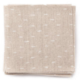 A stack of fabric swatches in a dotted diamond grid in white on a tan field.