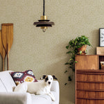 A living room with a dog on a couch and a wall papered in a painterly abstract print in white and mustard.