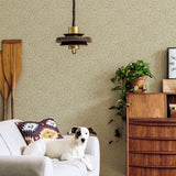 A living room with a dog on a couch and a wall papered in a painterly abstract print in white and mustard.