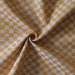 Close up of draped woven fabric with small scale checkerboard pattern in white and light orange.