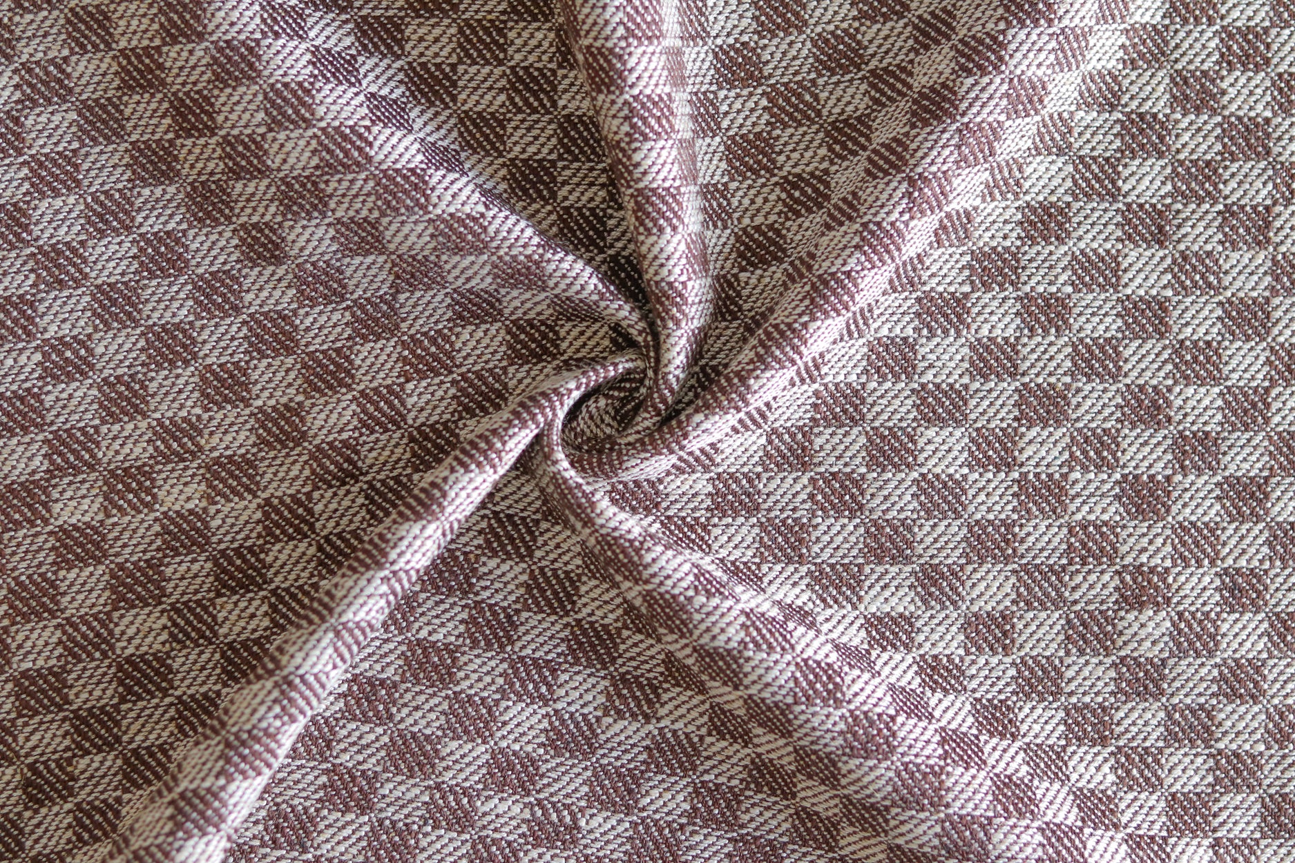 Close up of draped woven fabric with small scale checkerboard pattern in white and dark brown.