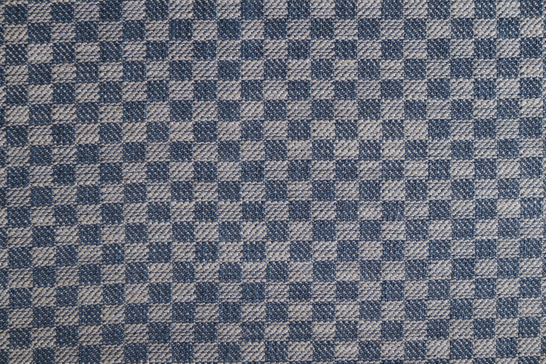 Close up of woven fabric with small scale checkerboard pattern in white and navy blue. 