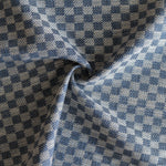 Close up of draped woven fabric with small scale checkerboard pattern in white and navy blue. 
