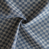 Close up of draped woven fabric with small scale checkerboard pattern in white and navy blue. 